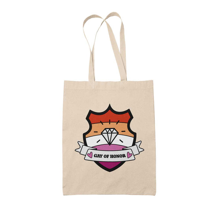 Natural coloured tote bag featuring a shield with a banner across it's front. Banner reads Gay of Honor. The background of the shield is the lesbian pride flag and there is a jewel icon in the centre.