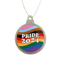 Load image into Gallery viewer, A flat silver glitter bauble on a white background. The bauble has a Pride 2024 design on the front with wavy lines in the colour of the progress pride flag.