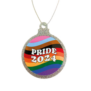 A flat silver glitter bauble on a white background. The bauble has a Pride 2024 design on the front with wavy lines in the colour of the progress pride flag.