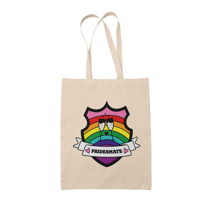 Natural coloured tote bag featuring a shield with a banner across it's front. Banner reads Pridesmate. The background of the shield is the Gilbert Baker pride flag and there is a pair of clinking champagne flutes in the centre.