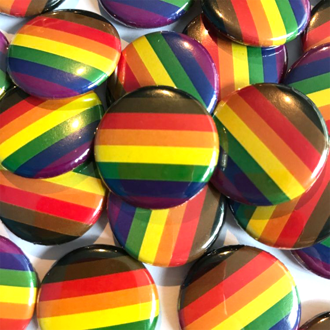 A pile of QPOC inclusive rainbow flag badges