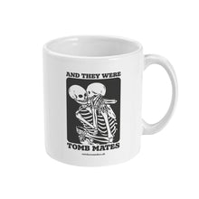 Load image into Gallery viewer, A white ceramic coffee mug with the handle on the right. The mug shows two skeletons embracing and the text &#39;And They Were Tomb Mates&#39;