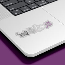 Load image into Gallery viewer, A silver laptop with a row of stickers featuring mummy-wrapped cats in monochrome, positioned on the bottom right corner of the laptop&#39;s surface. The cats are illustrated in black, white, grey, and purple, representing the asexual flag colours.