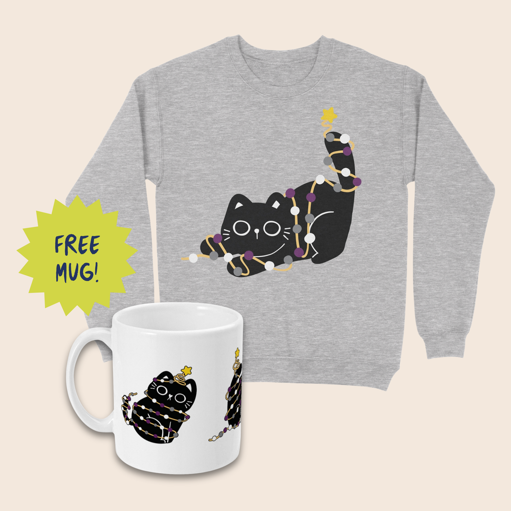 Grey Christmas jumper and white mug featuring black cats wrapped in purple, grey and white fairy lights with yellow stars. The mug sits in front of the jumper on a cream background, beside a lime-green starburst reading “FREE MUG!”