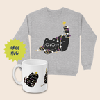 Grey Christmas jumper and white mug featuring black cats wrapped in purple, grey and white fairy lights with yellow stars. The mug sits in front of the jumper on a cream background, beside a lime-green starburst reading “FREE MUG!”