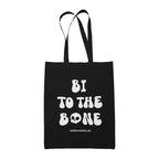 Black cotton tote bag featuring the slogan Bi To The Bone in white text