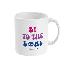 Load image into Gallery viewer, A white ceramic coffee mug with the handle on the right. The mug shows the slogan &#39;Bi To The Bone&#39; in the colours of the bisexual flag with a bone and a skull icon.
