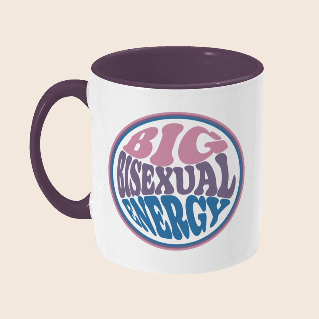 White mug with dark purple handle and interior. Circular text in pink, purple, and blue reads: “Big Bisexual Energy.”