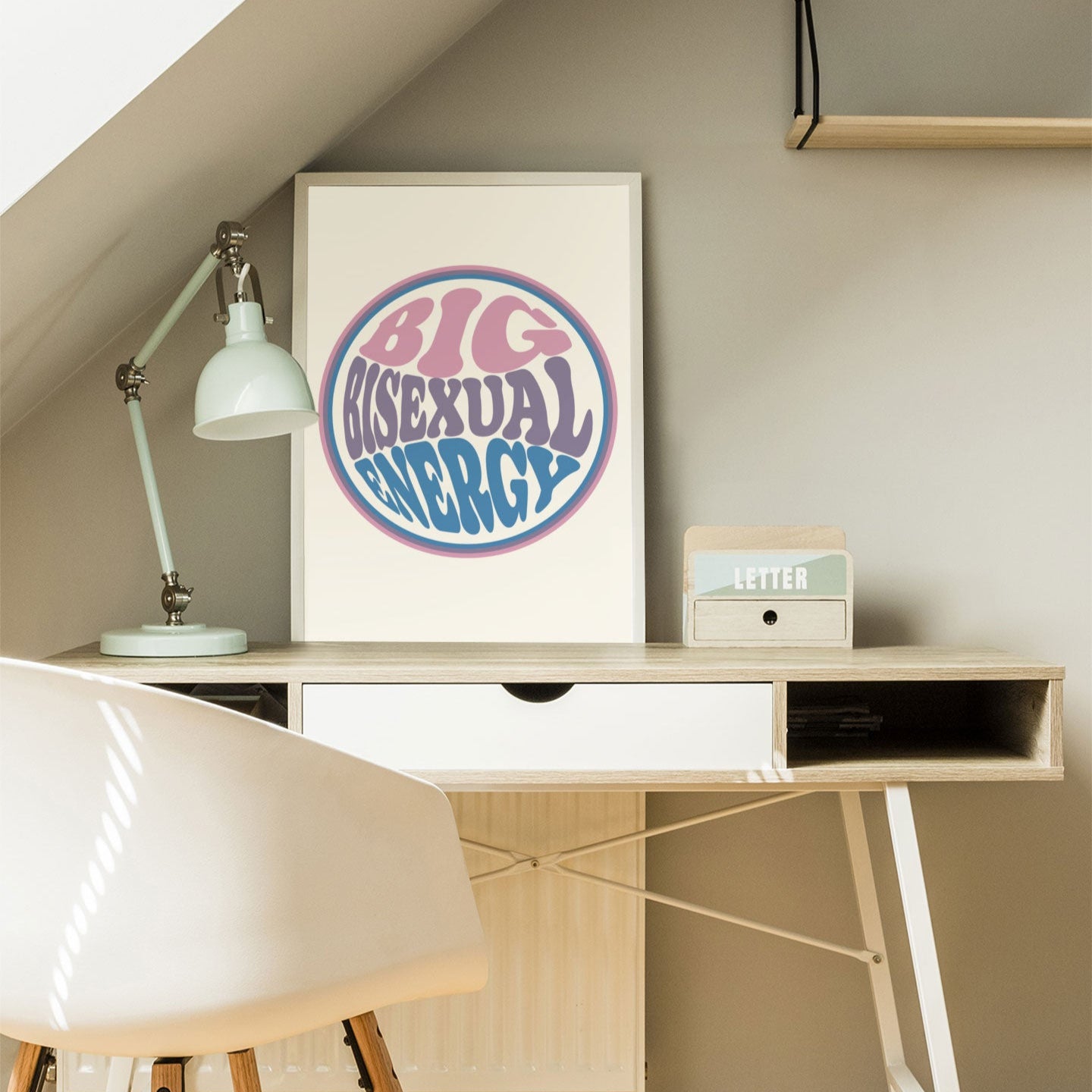 A Big Bisexual Energy print styled in a home office on a desk with a white chair, books, and a soft, natural light setting.