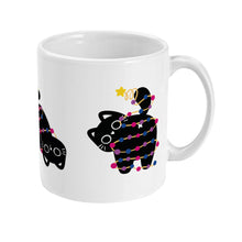 Load image into Gallery viewer, A white ceramic mug with a black cat standing up, with its tail wrapped in bisexual-themed Christmas lights. The lights are in pink, blue, and purple, and a star sits atop the cat&#39;s tail.