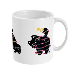 A white ceramic mug with a black cat standing up, with its tail wrapped in bisexual-themed Christmas lights. The lights are in pink, blue, and purple, and a star sits atop the cat's tail.