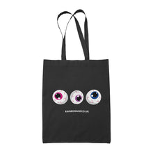 Load image into Gallery viewer, A black tote bag featuring three cartoonish eyeballs in a row. The eyeballs display different colours: one with a pink iris, one with a purple iris, and one with a blue iris. The text &quot;RAINBOWANDCO.UK&quot; is positioned below the eyeballs.