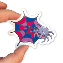 Load image into Gallery viewer, A hand holding a cute spider sticker with a bisexual pride web design. The web features pink, purple, and blue segments, symbolising the bisexual flag.