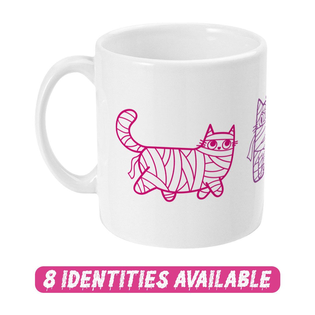 A white ceramic mug featuring a whimsical design of cartoon cats wrapped in mummy bandages, depicted in shades of pink and purple. The artwork highlights three cats in different playful poses, each showcasing their unique personality. Below the mug, a bold pink text reads "8 IDENTITIES AVAILABLE" in a dripping font, indicating the availability of this design in various identity options.