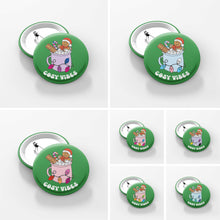 Load image into Gallery viewer, Image is split into seven squares, each one showing a close up of a green 38mm badge featuring retro text reading &#39;cosy vibes&#39;. Each badge shows a mug of hot chocolate with marshmallows and a gingerbread man wearing a Santa hat. A candy cane in the mug and lights around the mug are the colours of different pride flags.
