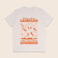 A vintage white short-sleeve crewneck t-shirt with a retro-style orange graphic on the front. The graphic features a cartoon sun character holding a flag and the text 'A day without LESBIANS is like a day without SUNSHINE'.