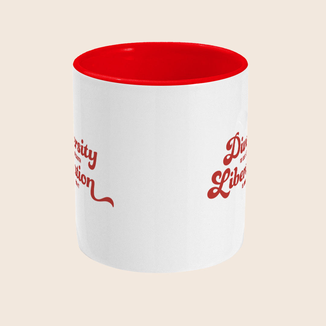 White ceramic mug with a red handle and red interior, featuring the slogan “Diversity Is Our Strength, Liberation Is Our Fight” in bold red retro-style lettering on the front.