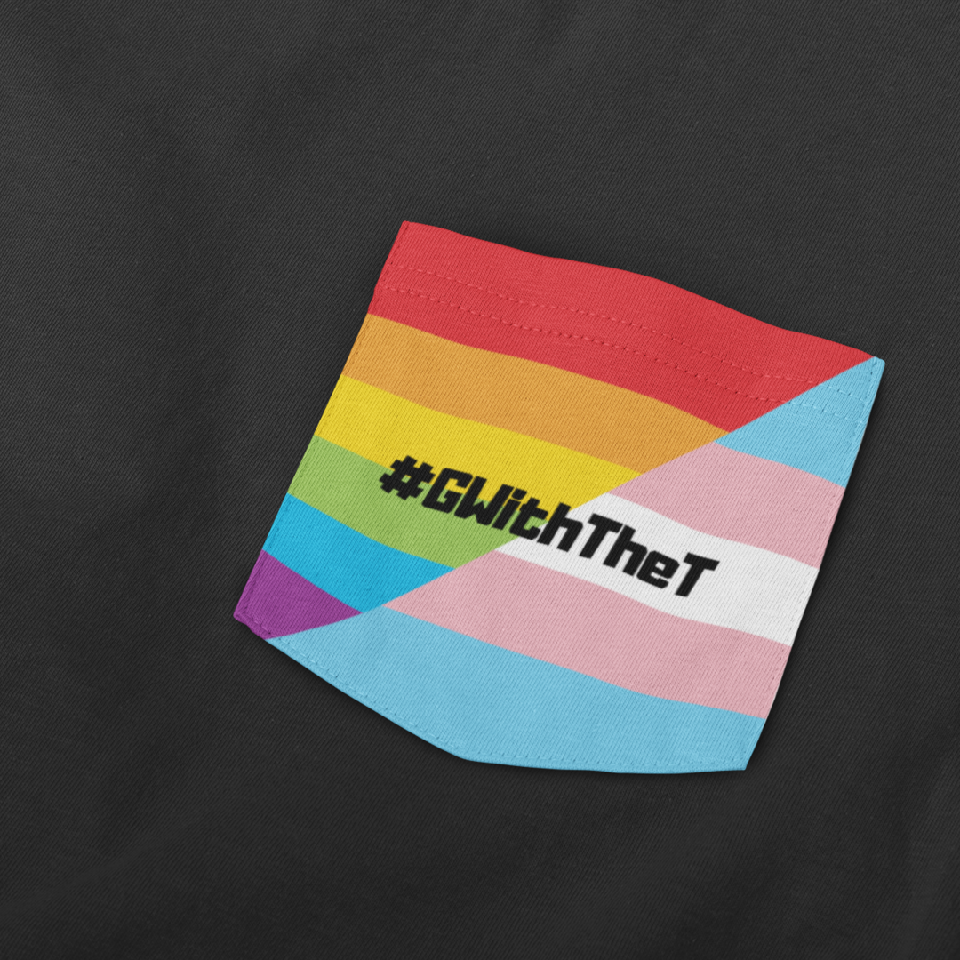 Close-up of a black t-shirt featuring a stitched fabric pocket with the Rainbow Pride Flag and Transgender Pride Flag with the hashtag "#GWithTheT" printed in bold black text across the centre.
