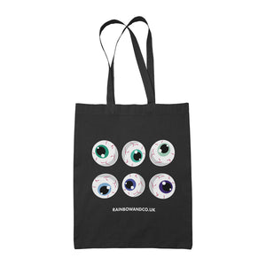 A black tote bag displaying six cartoonish eyeballs in two rows. The eyeballs are coloured in various shades of green and blue. The website "RAINBOWANDCO.UK" is written below the eyeballs.