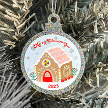 Load image into Gallery viewer, Close up of a white Christmas tree displaying a silver glitter bauble featuring a classic gingerbread house illustration with rainbow accents. Text reads Merry Christmas at the top and 2023 at the bottom.