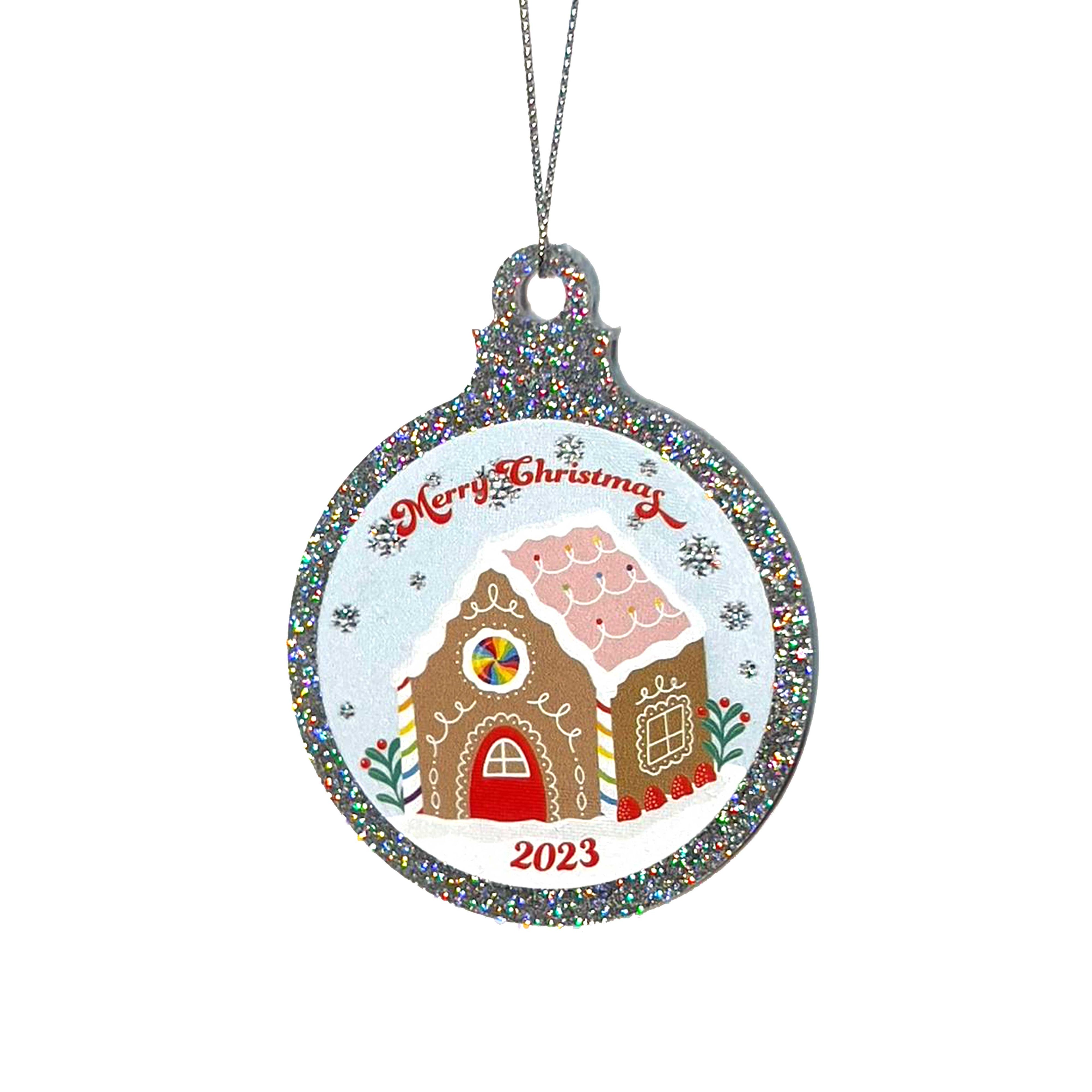 Close up of a silver glitter bauble featuring a classic gingerbread house illustration with rainbow accents. Text reads Merry Christmas at the top and 2023 at the bottom. It is held up by a silver string.