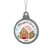 Load image into Gallery viewer, Close up of a silver glitter bauble featuring a classic gingerbread house illustration with rainbow accents. Text reads Merry Christmas at the top and 2023 at the bottom. It is held up by a silver string.