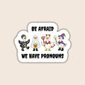 Be Afraid We Have Pronouns sticker featuring four geese dressed as a skeleton, ghost, devil and wizard on a beige background.