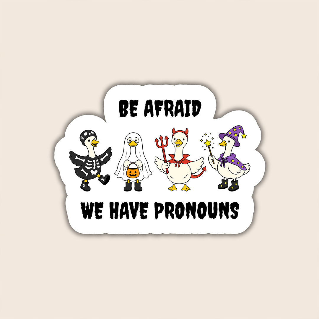 Be Afraid We Have Pronouns sticker featuring four geese dressed as a skeleton, ghost, devil and wizard on a beige background.