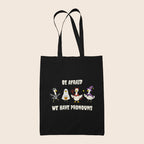 Black cotton tote bag featuring four geese in Halloween costumes with the words Be Afraid We Have Pronouns