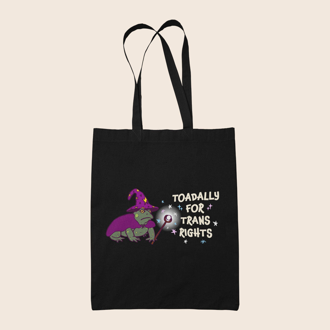 Black cotton tote bag featuring a wizard toad in purple with the words Toadally For Trans Rights