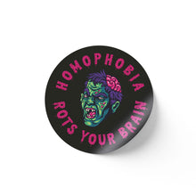 Load image into Gallery viewer, A round black sticker with a vibrant illustration of a green-skinned zombie head with a partially exposed brain, surrounded by the text &quot;HOMOPHOBIA ROTS YOUR BRAIN&quot; in pink, dripping letters.