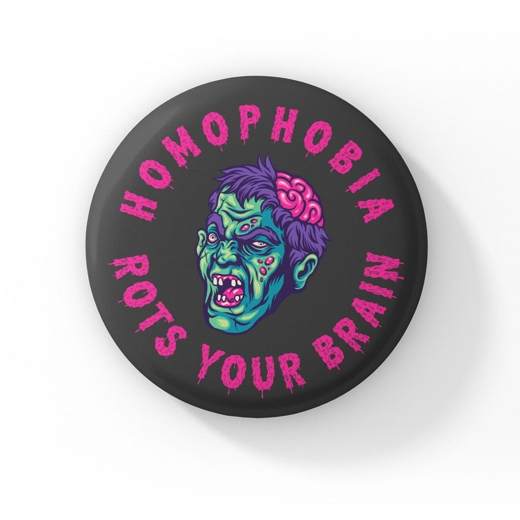 A round badge with a black background featuring a cartoon zombie head with green skin, purple hair, and exposed brain. The text "HOMOPHOBIA ROTS YOUR BRAIN" is written in bold, dripping pink letters around the zombie head.