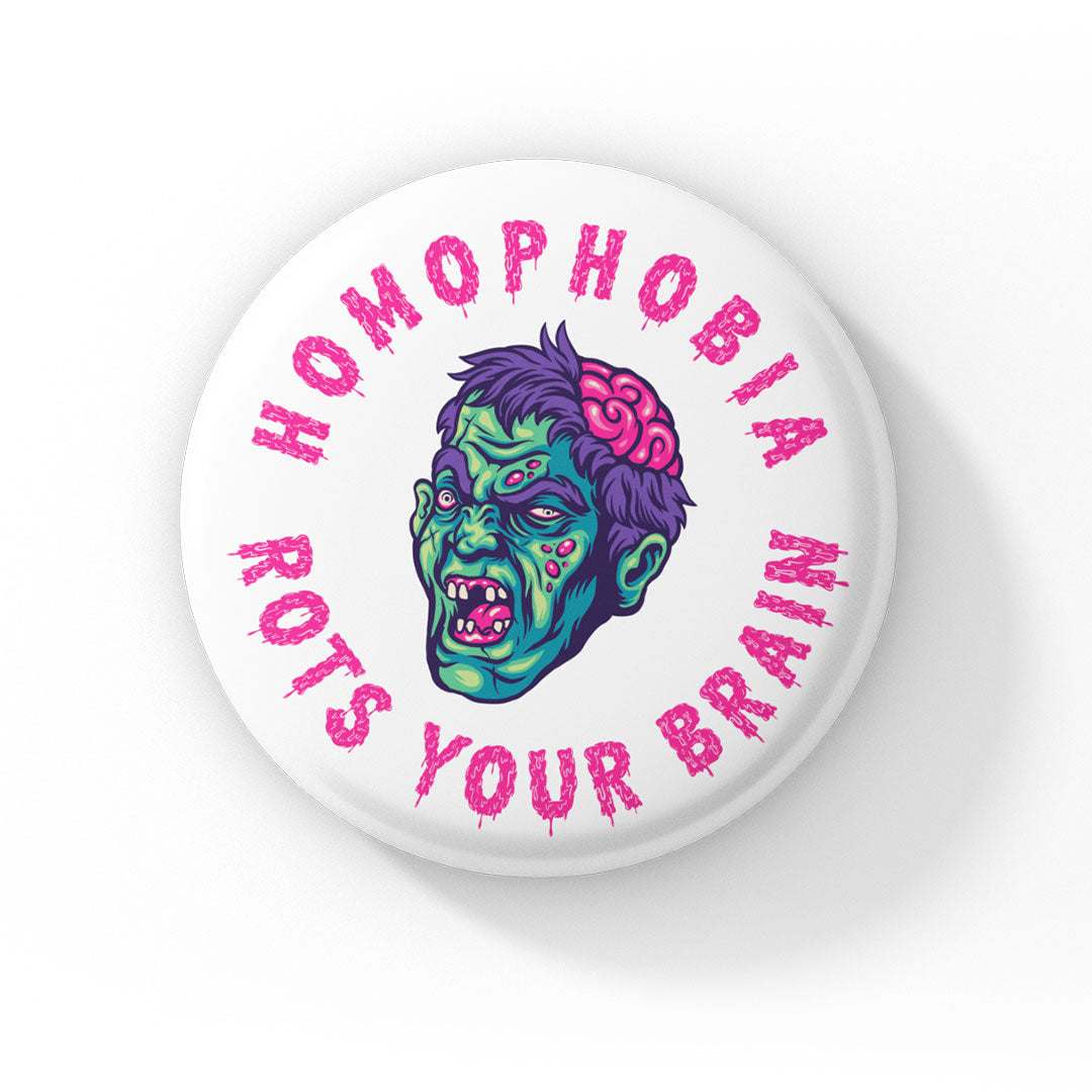 A round badge with a white background displaying a cartoon zombie head with green skin, purple hair, and exposed brain. The text "HOMOPHOBIA ROTS YOUR BRAIN" is written in bold, dripping pink letters encircling the zombie head.