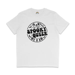 A white T-shirt with the phrase "In My Spooky Queer Era" printed in bold, dripping black letters, surrounded by bat and skull illustrations, giving a Halloween-themed look. The shirt is laid flat on a white background.