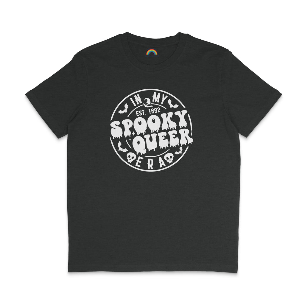 A dark heather grey T-shirt featuring the same "In My Spooky Queer Era" design in white, with dripping letters and Halloween-themed illustrations. The shirt is laid flat on a matching dark background.