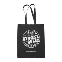 Load image into Gallery viewer, A black tote bag featuring a white circular design with the text &quot;In My Spooky Queer Era&quot; in a spooky font, surrounded by bats and skulls. The year &quot;Est. 1692&quot; is written above the words &quot;Spooky Queer.&quot; The bottom of the bag shows the website &quot;RAINBOWANDCO.UK&quot;.