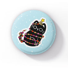 Load image into Gallery viewer, A black cat wrapped in string lights in the colours of the lesbian flag (orange, pink, and white), with its tail playfully wrapped in the lights, sitting on a light blue background with snowflakes.