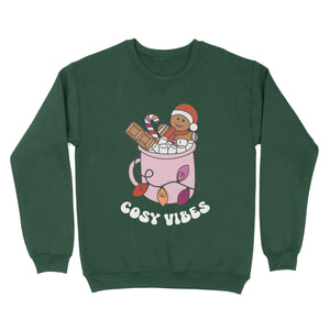Bottle Green sweatshirt featuring retro text reading 'cosy vibes'. The image shows a mug of hot chocolate with marshmallows and a gingerbread man wearing a Santa hat. A candy cane in the mug and lights around the mug are the colours of the lesbian pride flag.