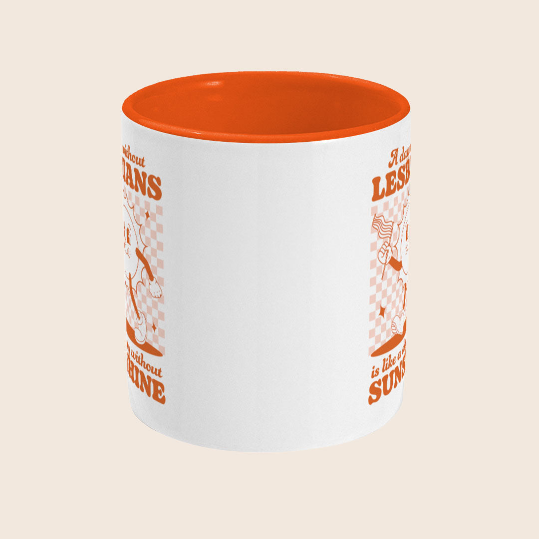 White ceramic mug with an orange handle and interior, featuring a retro-style orange checkerboard design with a smiling sun character holding a pride flag. The text reads: “A day without LESBIANS is like a day without SUNSHINE.”