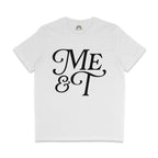 Flat lay of a white t-shirt with bold black text reading “Me & T” in a decorative serif font. The inside neckline features a rainbow logo with the website rainbowandco.uk.
