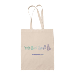 A natural canvas tote bag displaying a line drawing of six mummy cats in shades of green, teal, and blue, representing the colours of the Gay pride flag. Each cat is wrapped like a mummy, with distinctive poses and expressions.