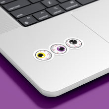 Load image into Gallery viewer, Three circular stickers with eyeball designs are placed on the bottom corner of a silver laptop. The irises are yellow, purple, and black, representing the non-binary pride flag.