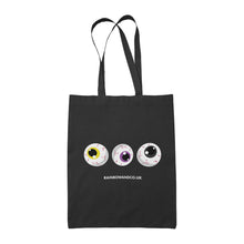 Load image into Gallery viewer, A black tote bag featuring three cartoonish eyeballs in a row. The eyeballs have different colours: yellow, purple, and black. Below them is the text &quot;RAINBOWANDCO.UK&quot;.