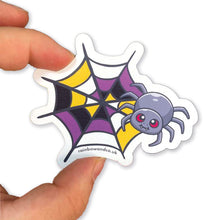 Load image into Gallery viewer, A hand holding a cute spider sticker with a non-binary pride web design. The web features yellow, white, purple, and black segments, representing the non-binary flag.