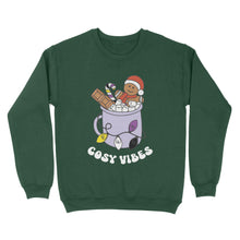 Load image into Gallery viewer, Bottle Green sweatshirt featuring retro text reading &#39;cosy vibes&#39;. The image shows a mug of hot chocolate with marshmallows and a gingerbread man wearing a Santa hat. A candy cane in the mug and lights around the mug are the colours of the non binary pride flag.