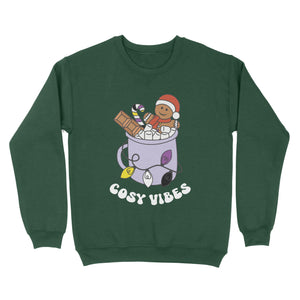 Bottle Green sweatshirt featuring retro text reading 'cosy vibes'. The image shows a mug of hot chocolate with marshmallows and a gingerbread man wearing a Santa hat. A candy cane in the mug and lights around the mug are the colours of the non binary pride flag.