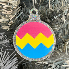 Load image into Gallery viewer, Close up of a white Christmas tree displaying a silver glitter bauble featuring a classic zig zag design in the colours of the pansexual pride flag.
