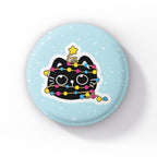A black cat wrapped in string lights in the colours of the pansexual flag (pink, yellow, and blue), standing upright on a light blue background with snowflakes.