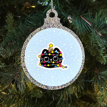 Load image into Gallery viewer, A sparkling Christmas bauble featuring a black cat wrapped in fairy lights in the colours of the pansexual pride flag. The cat sits contentedly with a star on its head against a snowy background, hanging on a Christmas tree.