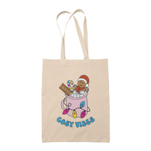 Load image into Gallery viewer, Natural tote bag featuring retro text reading &#39;cosy vibes&#39;. The image shows a mug of hot chocolate with marshmallows and a gingerbread man wearing a Santa hat. A candy cane in the mug and lights around the mug are the colours of the pansexual pride flag.